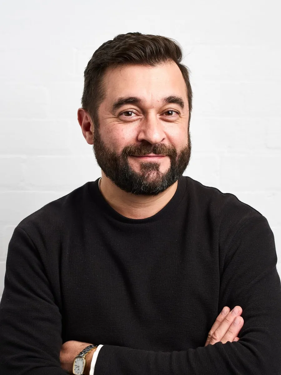 Yury Kuczko, founder of Artmost, photographed against a white brick wall.
